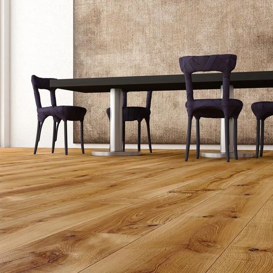 Vier lila Stühle sind um einen großen schwarzen Tisch in einem Raum mit Holzböden und einer strukturierten braunen Wand angeordnet.