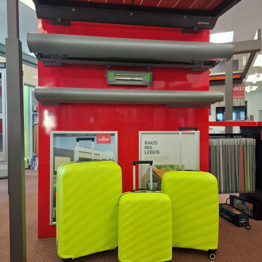 Drei neongrüne Koffer sind in einem Geschäft ausgestellt, mit einer roten Wand im Hintergrund.