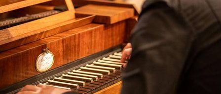 Ein Mann spielt Klavier in einem Raum, in dem andere Leute hinter ihm sitzen.