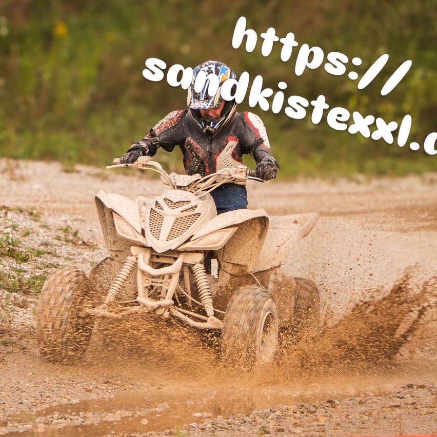 Eine Person fährt ein Quad auf einem schlammigen Feldweg. Sie trägt einen Helm und Handschuhe. Der Hintergrund ist verschwommen mit viel Grün.