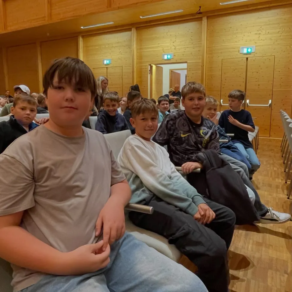 Eine Gruppe von Jungen sitzt in einem Klassenzimmer. Ein Junge schaut in die Kamera.