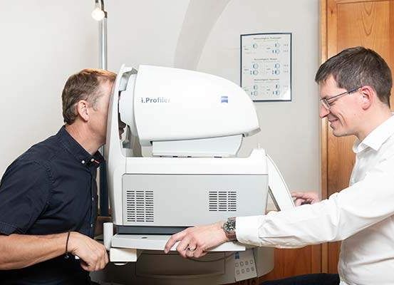 Zwei Männer sind in einem Raum, einer überprüft mit einem Gerät sein Sehvermögen.