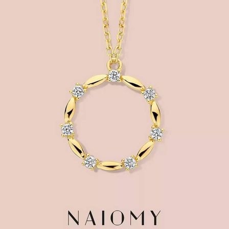 Eine goldene Anhänger-Halskette mit Diamanten in einem kreisförmigen Muster auf einem rosa Hintergrund.