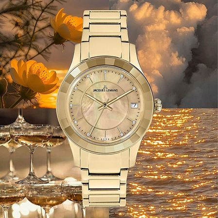 Eine goldene Jacques Lemans Uhr mit einem Perlmutt-Zifferblatt und Diamantbesatz vor dem Hintergrund eines untergehenden Sonnen, Blumen und Weingläser.