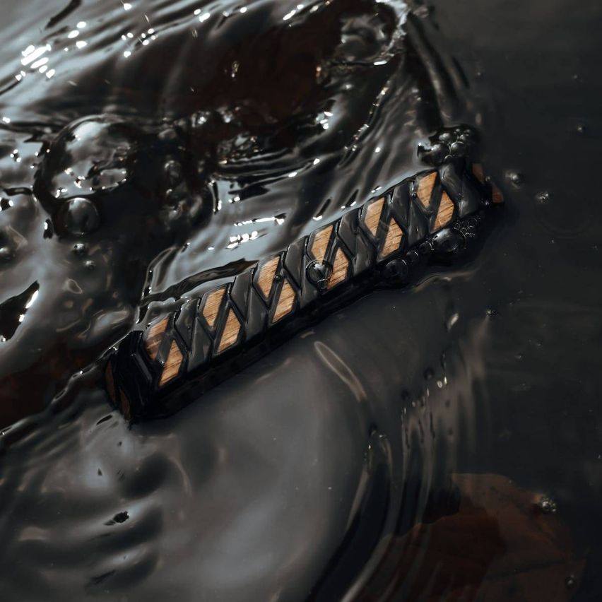 Ein schwarz-braunes Objekt, das einem Griff ähnelt, schwimmt in dunklem Wasser. Der Gegenstand hat geometrische Muster und eine glänzende Oberfläche.