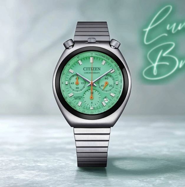 Eine Citizen Chronographenuhr mit grünem Zifferblatt, silbernem Armband und silbernem Gehäuse. Die Zeit ist 1:55.