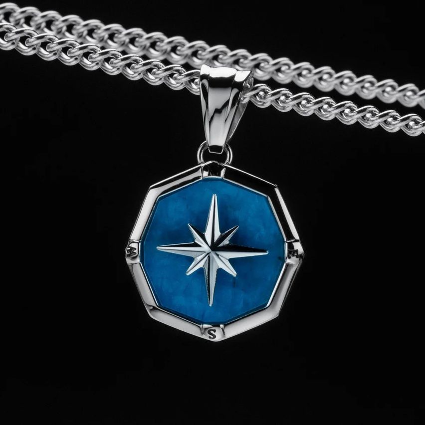 Eine Silberkette mit einem sechseckigen Anhänger mit blauer Mitte und einem weißen Stern. Der Anhänger hat einen silbernen Umriss.