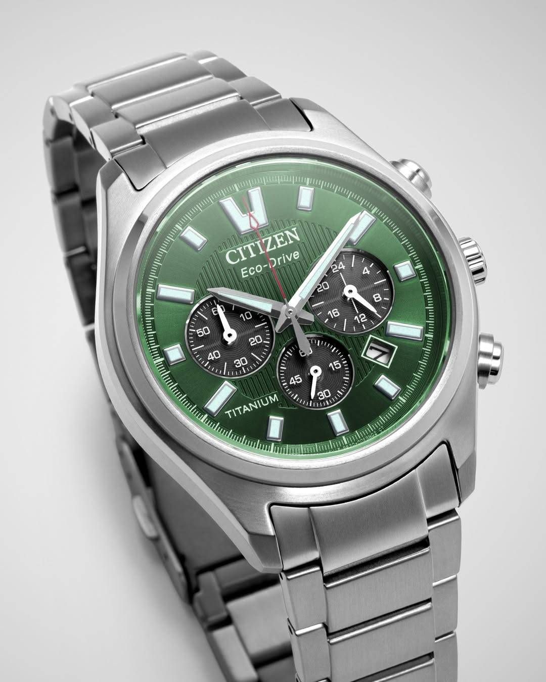Eine Edelstahl-Citizen Eco-Drive Uhr mit grünem Zifferblatt. Das Uhrengehäuse hat mehrere Hilfszifferblätter und Markierungen. Die Uhrzeit zeigt 11:45 Uhr an.