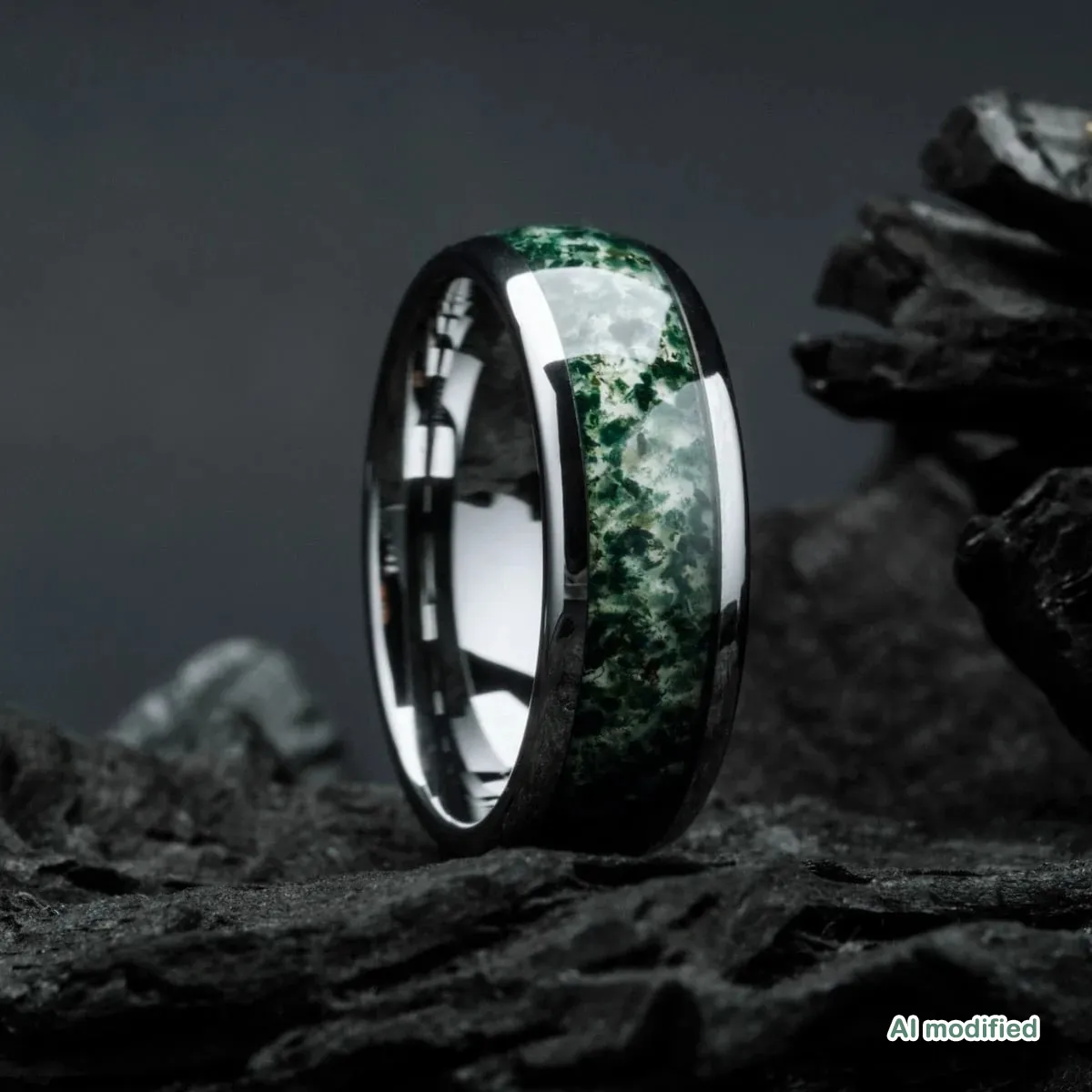 Ein Ring mit einem grünen Edelsteinband liegt auf einem Haufen Steine.