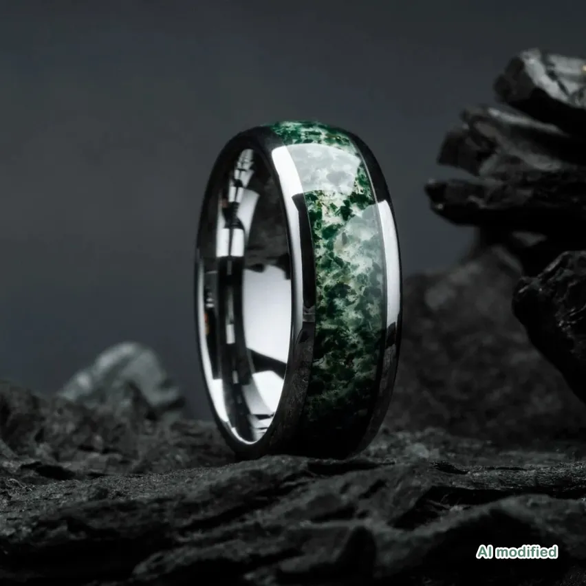 Ein Ring mit einem grünen Edelsteinband liegt auf einem Haufen Steine.