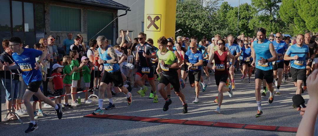 Läufer nehmen an einem Marathon teil. Zuschauer jubeln von den Rängen. Ein gelber Bogen mit dem Namen Niederoesterrein markiert die Ziellinie.