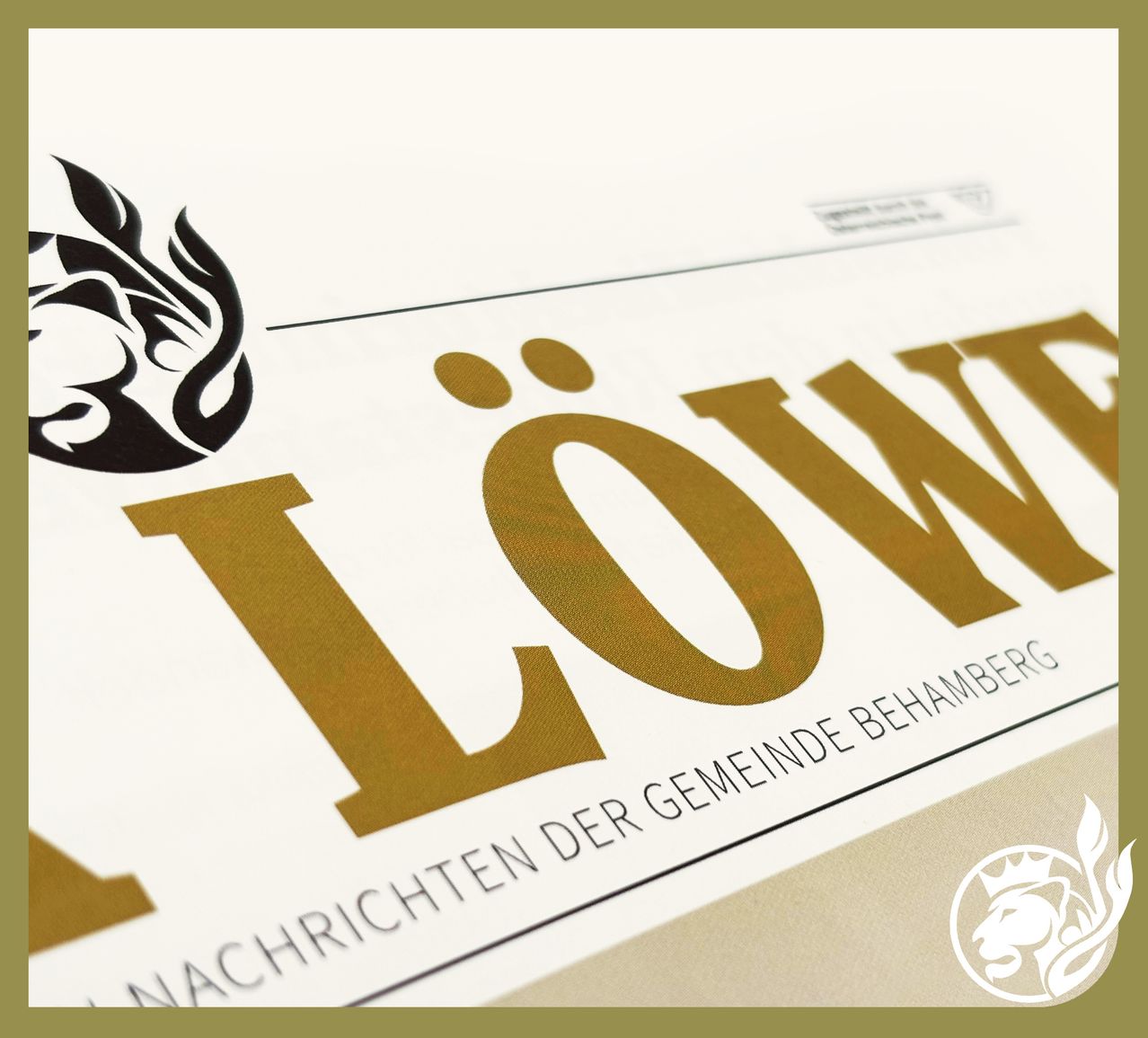 Nahaufnahme eines weißen Papiers mit einem goldenen Logo, das 'Low' liest, mit einem Löwenkopf-Silhouette. Unter dem Logo steht der Text 'Nachrichten der Gemeinde Behamberg'.