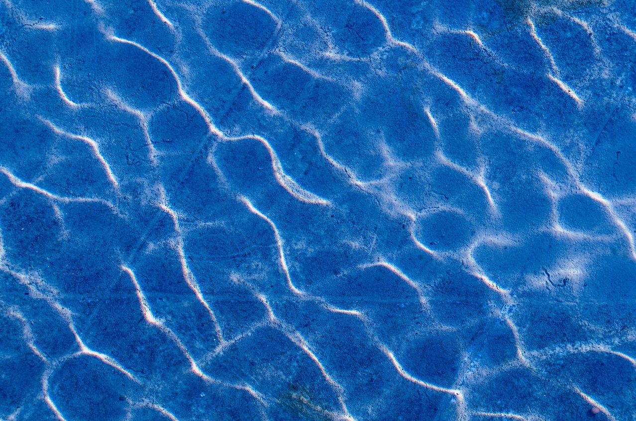 Close-up view of blue water with ripples and light reflections, creating a textured pattern.
