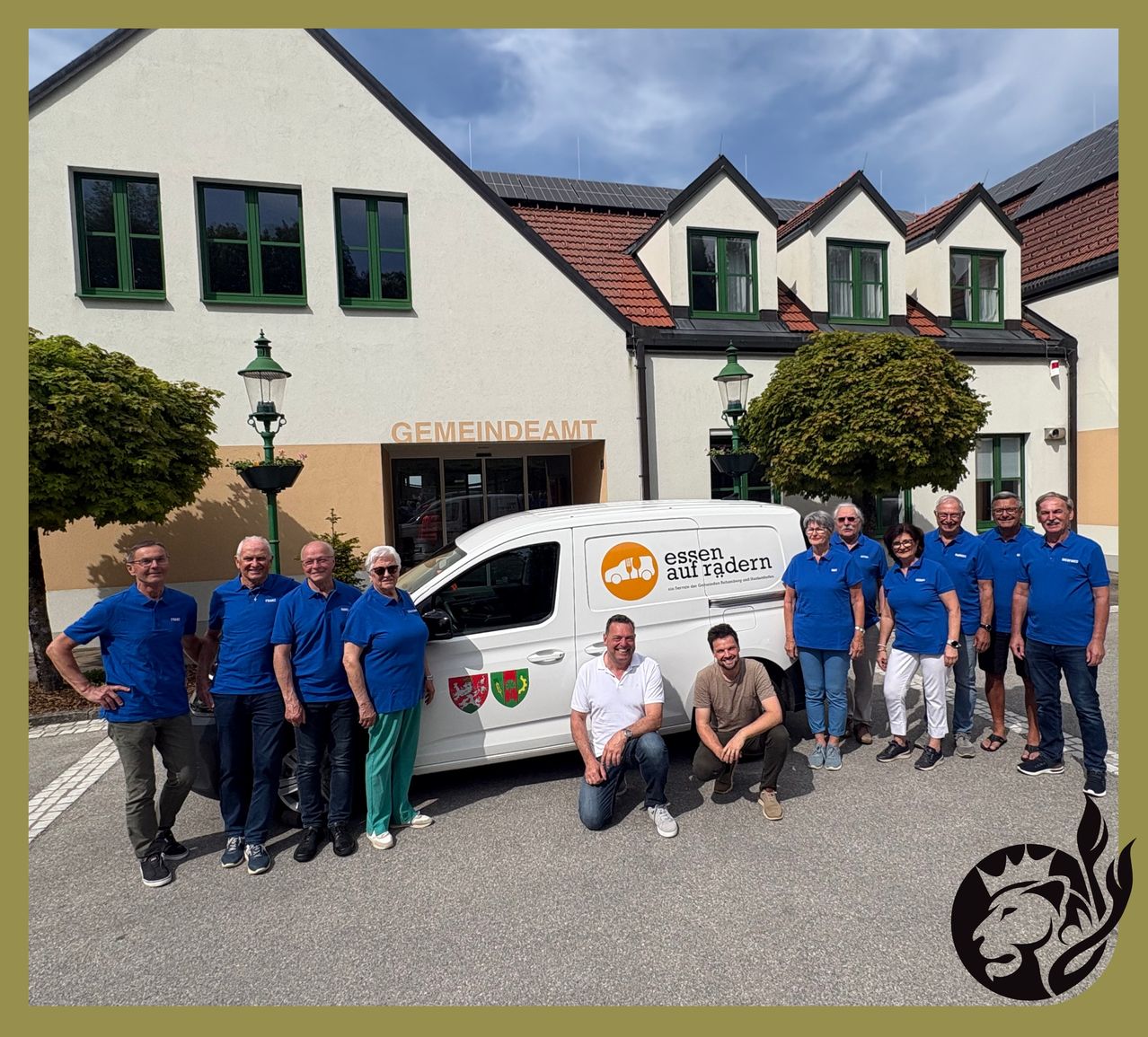 A group of people in blue uniforms are posing in front of a van with the text essen auf rädern. Behind them is a building with the text gemeindeamt.