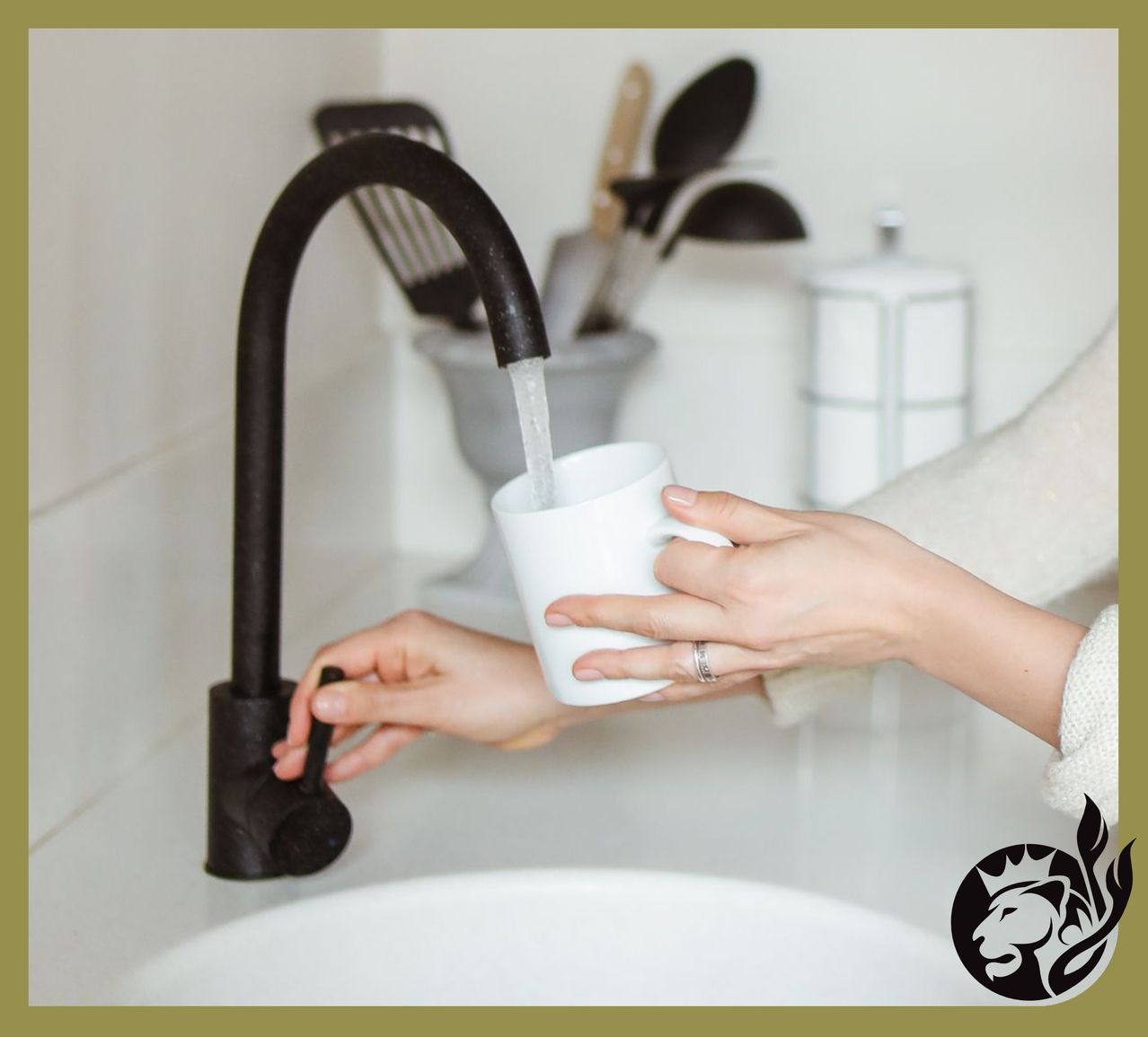 Eine Person füllt in einer Küche einen weißen Becher mit Wasser aus einem Wasserhahn. Hinter ihr stehen Utensilien in einer Schüssel und ein Glas.