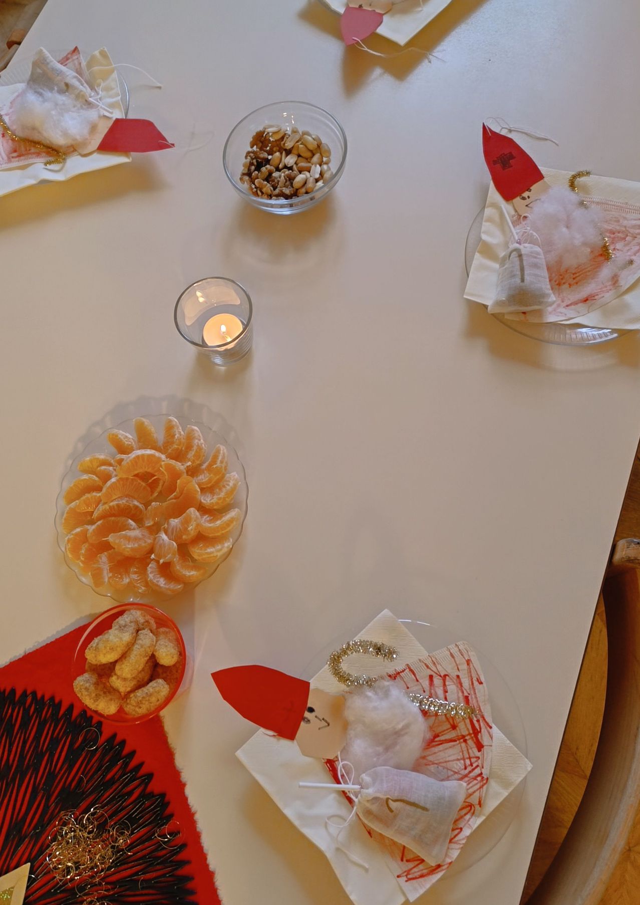 Ein Tisch mit einer Schüssel Orangen, einer Schüssel Nüssen, einer Kerze und Servietten.