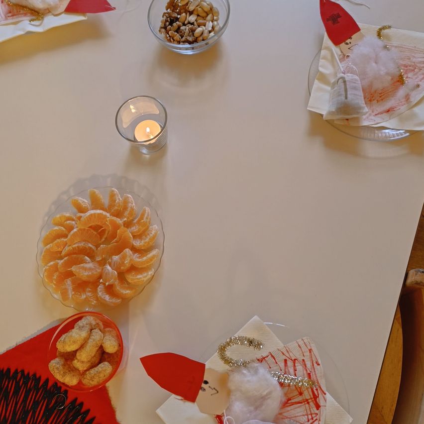 Ein Tisch mit einer Schüssel Orangen, einer Schüssel Nüssen, einer Kerze und Servietten.