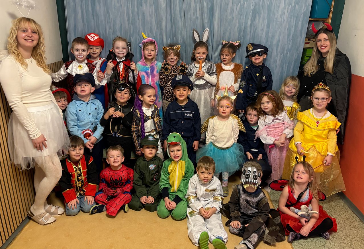 Eine Gruppe von Kindern in verschiedenen Kostümen, darunter ein Pirat, ein Hase, ein Einhorn, ein Polizist und ein Superheld, posiert für ein Foto.