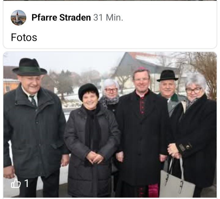 Sechs Menschen in Winterkleidung posieren für ein Foto. Sie stehen draußen in der Nähe eines Gebäudes mit Dach und Turm. Der Mann links trägt einen Hut.