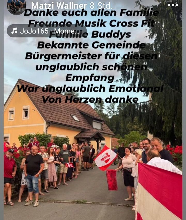 Eine Gruppe von Menschen steht vor einem Haus mit einer roten Flagge und dankt für einen unglaublichen Empfang. Sie stehen mit Freunden und Familie und feiern gemeinsam.