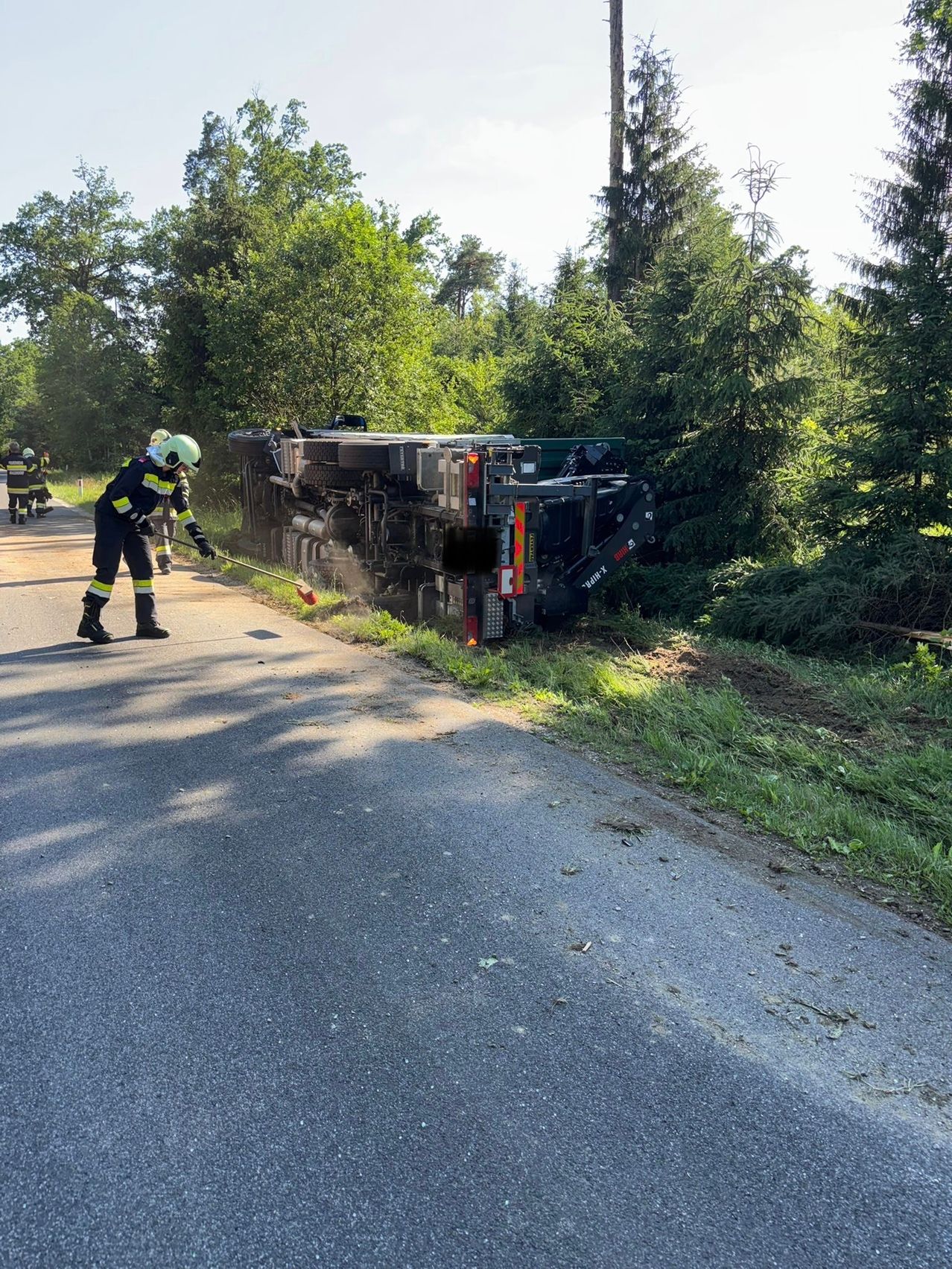Feuerwehrleute versuchen, ein Feuer in einem umgestürzten Lastwagen am Straßenrand zu löschen.