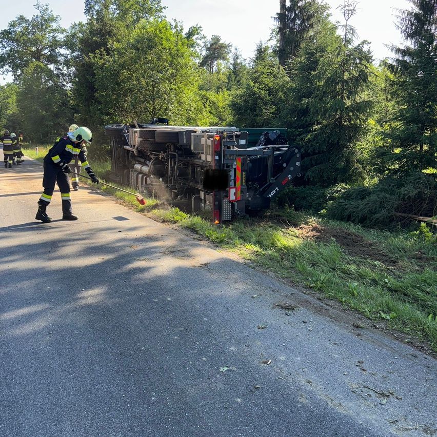Feuerwehrleute versuchen, ein Feuer in einem umgestürzten Lastwagen am Straßenrand zu löschen.