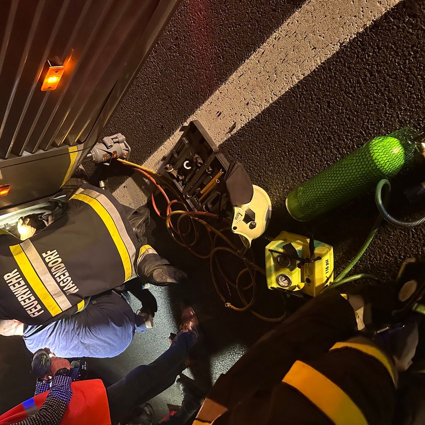 Feuerwehrleute arbeiten am Boden mit Ausrüstung um sie herum. Eine Person liegt, und eine andere steht. Eine grüne Sauerstoffflasche ist in der Nähe.