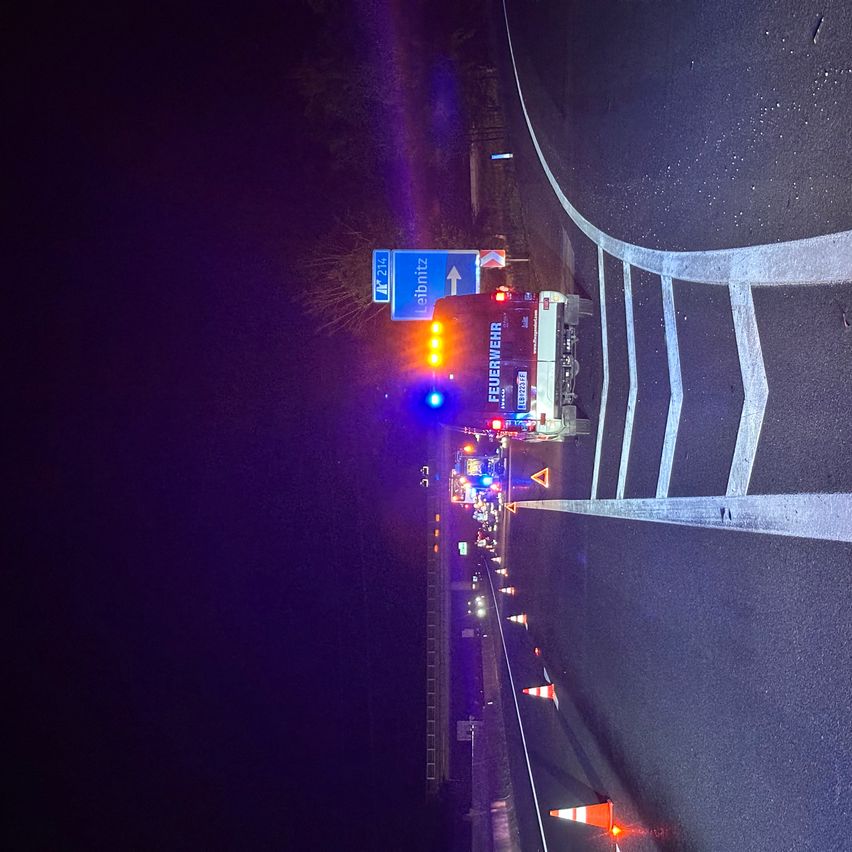 Ein Feuerwehrfahrzeug mit eingeschalteten Lichtern steht am Straßenrand, möglicherweise als Reaktion auf einen Vorfall.