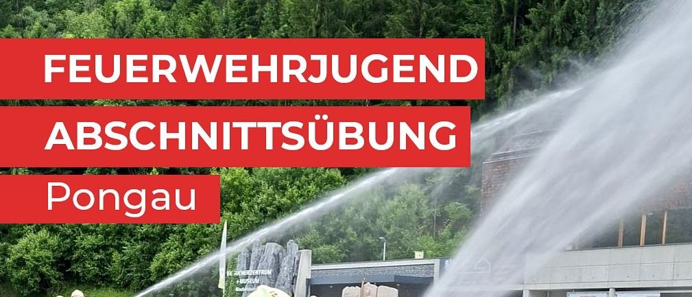 Zwei Feuerwehrleute in Uniform üben mit einem Schlauch im Freien, vor einem Gebäude und Bäumen im Hintergrund.