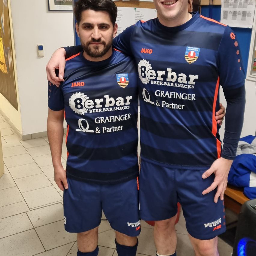Two men in sports jerseys, standing and posing for a photo in a locker room. One man has the number 8 on his jersey, and both have the word 'Grafinger' on their jerseys.
