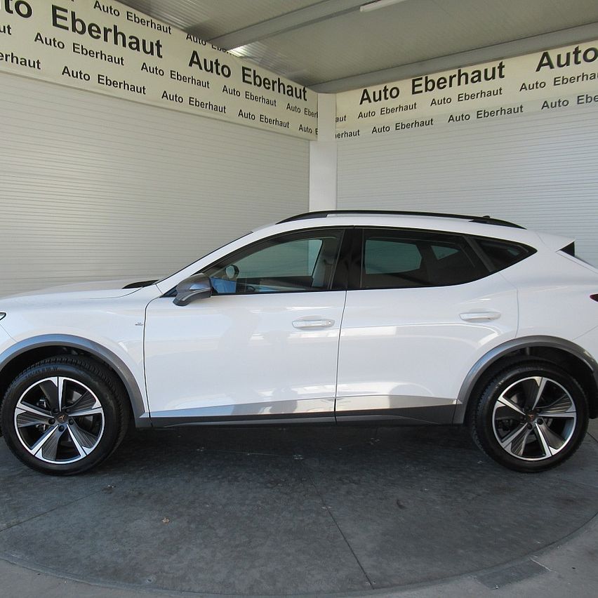 Ein weißer SUV steht in einem Ausstellungsraum mit Auto Eberhaut-Schildern an den Wänden. Das Fahrzeug hat ein modernes Design mit schlanken Linien und silbernen Felgen.