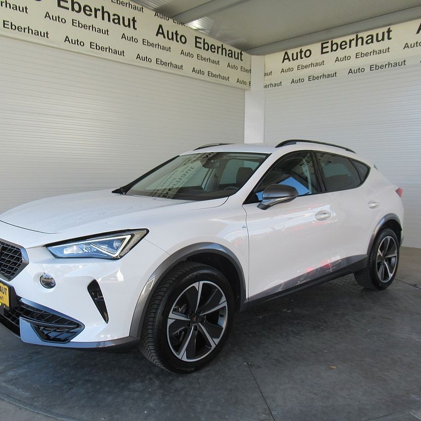 Ein weißer SUV mit einem gelben Nummernschild ist in einer Garage geparkt, deren weiße Wand wiederholt den Text 'Auto Eberhaut' aufweist.