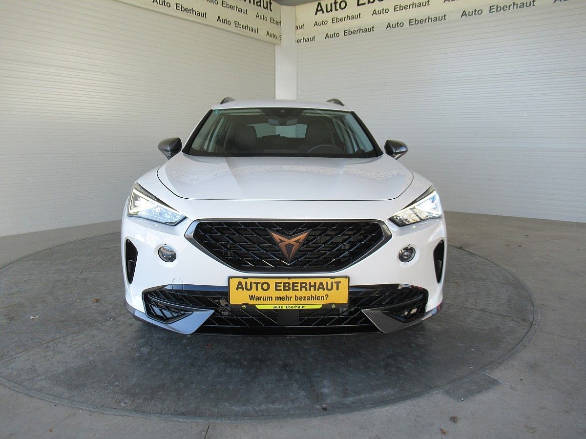 Ein weißer Wagen mit einem gelben Nummernschild, auf dem AUTO EBERHAU steht, ist in einer Garage geparkt. Der vordere Stoßfänger des Autos hat ein Sternlogo. Hinter dem Auto befinden sich weiße Wände mit Text.