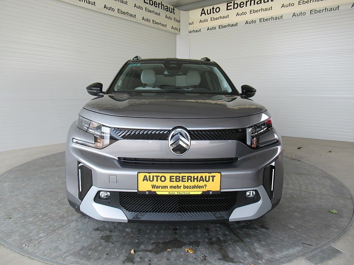 A gray Volkswagen SUV with a yellow license plate is parked in front of a garage with the name Auto Eberhaut.