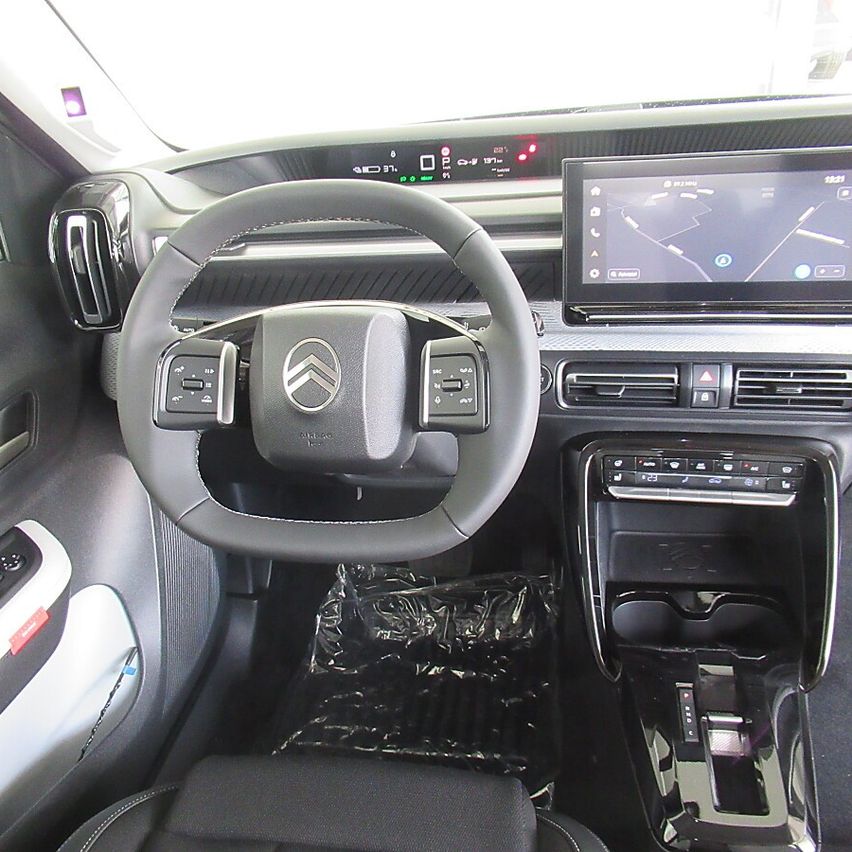 Interior of a modern car showing the steering wheel, dashboard with a navigation screen, and control buttons.