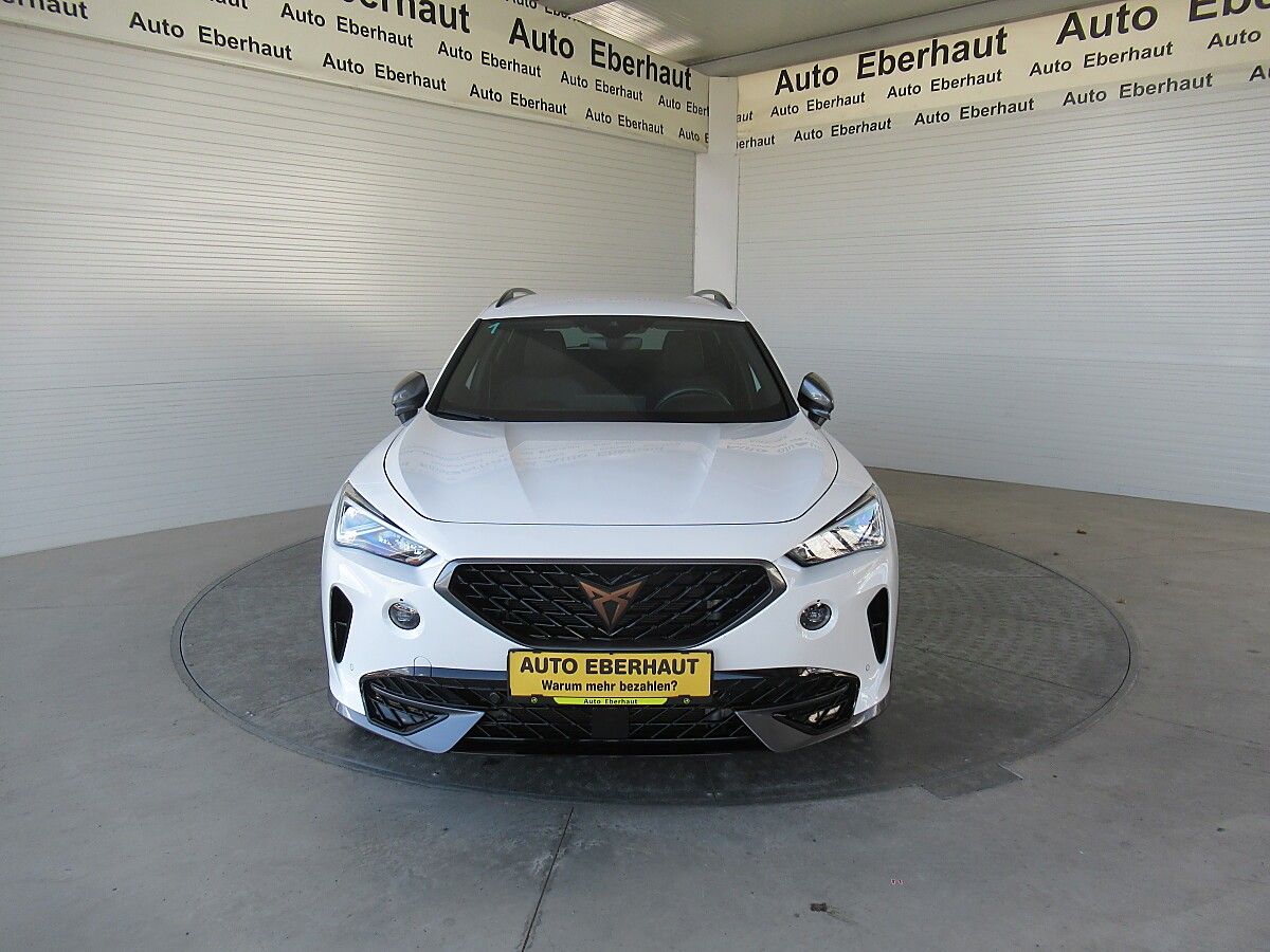 A white car with a yellow license plate is parked in a garage with walls that have the text 'Auto Eberhaut'.