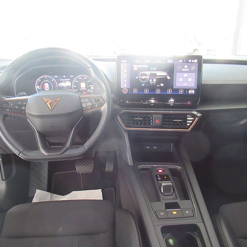 Interior of a modern car with a steering wheel, dashboard displaying various vehicle information, and a central touchscreen infotainment system.