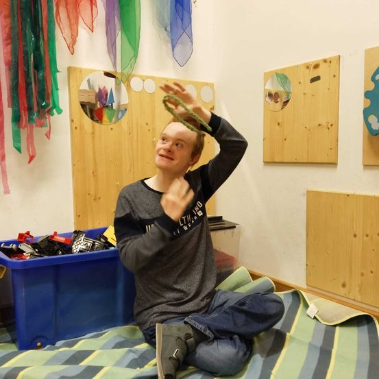 Bild enthält, Indoors, Interior Design, Pants, Person, Sitting, Portrait, Gun