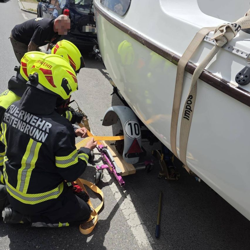 Feuerwehrleute in Schutzausrüstung arbeiten daran, ein Boot an einem Auto zu befestigen. Das Boot hat die Nummer 10 auf der Rückseite und wird mit Gurten befestigt.