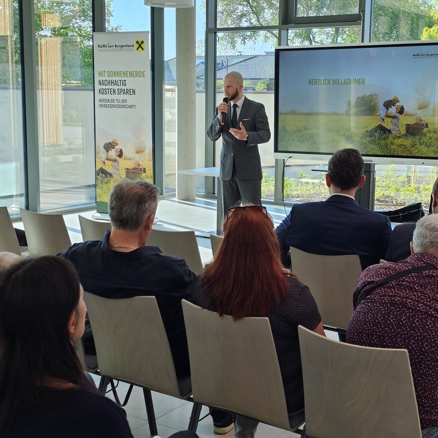 Ein Mann hält eine Präsentation über Kosteneinsparungen durch Solarenergie für eine Gruppe von Personen in einem Konferenzraum.