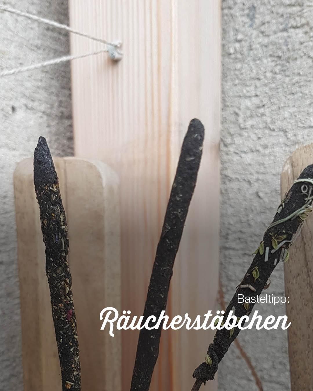 Drei Räucherstäbchen sind auf einer hölzernen Oberfläche angeordnet, mit einem unscharfen Hintergrund. Die Stöcke sind verkohlt und haben grüne Blätter darauf. Der Text auf dem Bild lautet 'Basteltipp:' und 'Räucherstäbchen'.