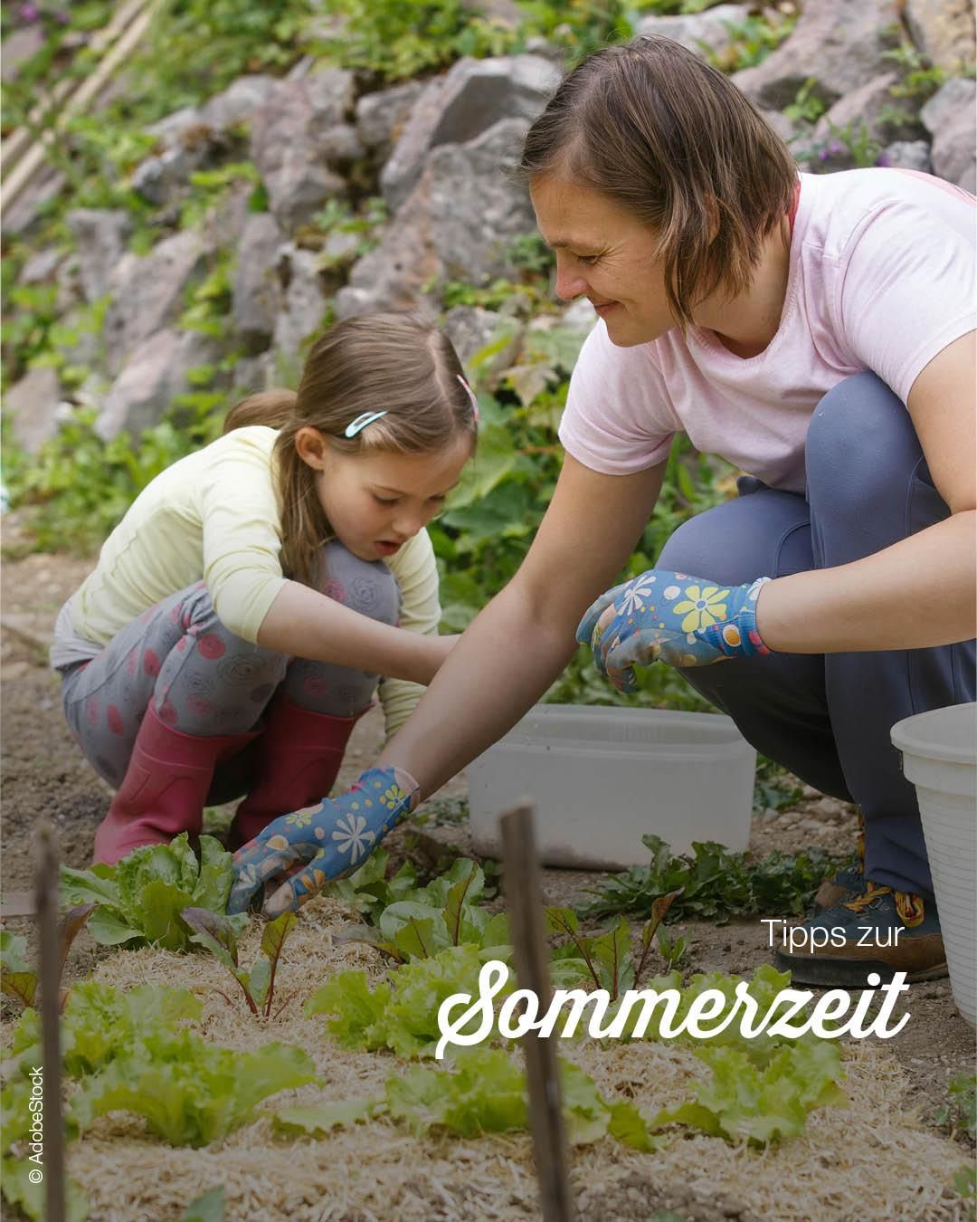 Eine Frau und ein kleines Mädchen gärtnern gemeinsam. Das Mädchen pflückt Blätter, und die Frau gibt ihr Anweisungen.