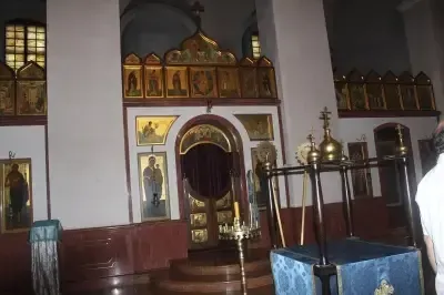 Ein kunstvoll verzierter Kapelleninnenraum mit goldenen Ikonen, einer zentralen Tür mit einem dunklen Vorhang und einem blauen Altarstück davor.