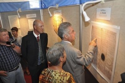 Mehrere Personen stehen vor einer Wand und betrachten ein großes Poster mit einer Karte und einem Loch in der Mitte. Ein Mann zeigt auf das Poster.