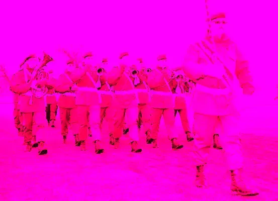 Eine Marschkapelle in roten Uniformen wird von hinten gesehen, mit Trompeten in der Front, auf einem rosa Hintergrund unterwegs.