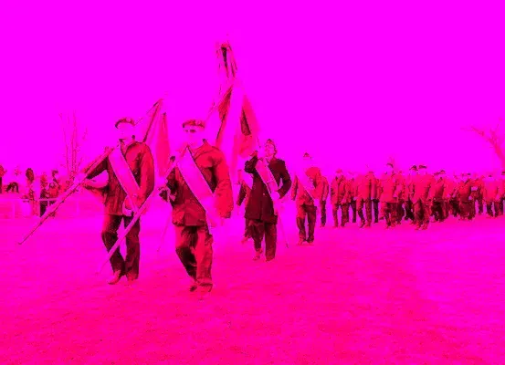 Eine Gruppe von Personen in roten Gewändern marschiert mit Fahnen vor einem rosa Hintergrund.