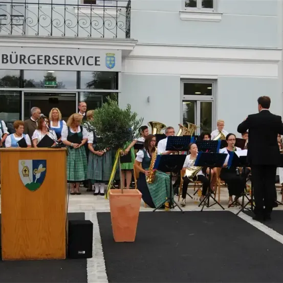 Eine Gruppe von Menschen, die vor einem Gebäude mit dem Schild Burgerservice spielen, sie spielen verschiedene Instrumente wie Saxophon, Trompete und Posaune.