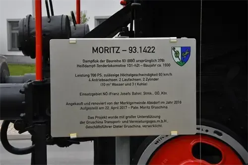 Ein Schild an einer Dampflokomotive zeigt ihren Namen, MORITZ-93.1422. Die Lokomotive war ursprünglich Nummer 378. Es handelt sich um eine Dampftenderlokomotive aus dem Jahr 1930 mit einer Leistung von 700 PS und einer Höchstgeschwindigkeit von 60 km/h. Das Schild enthält auch das Logo der Gemeinde Absorf.