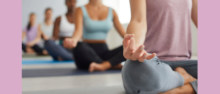 Eine Gruppe von Frauen praktiziert Klangmeditation, sitzt in Lotusposition auf Yogamatten mit einem rosa Hintergrund und einem Logo.
