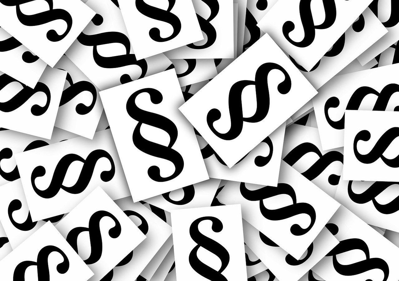 Ein schwarz-weißes Muster von Rechtssymbolen wird angezeigt. Jedes Symbol ist auf ein quadratisches Stück Papier gedruckt und sie sind übereinander gestapelt.